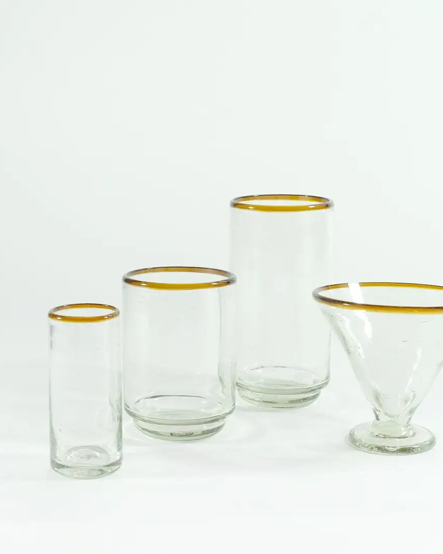Set of clear glass tumblers with gold rims on a white background