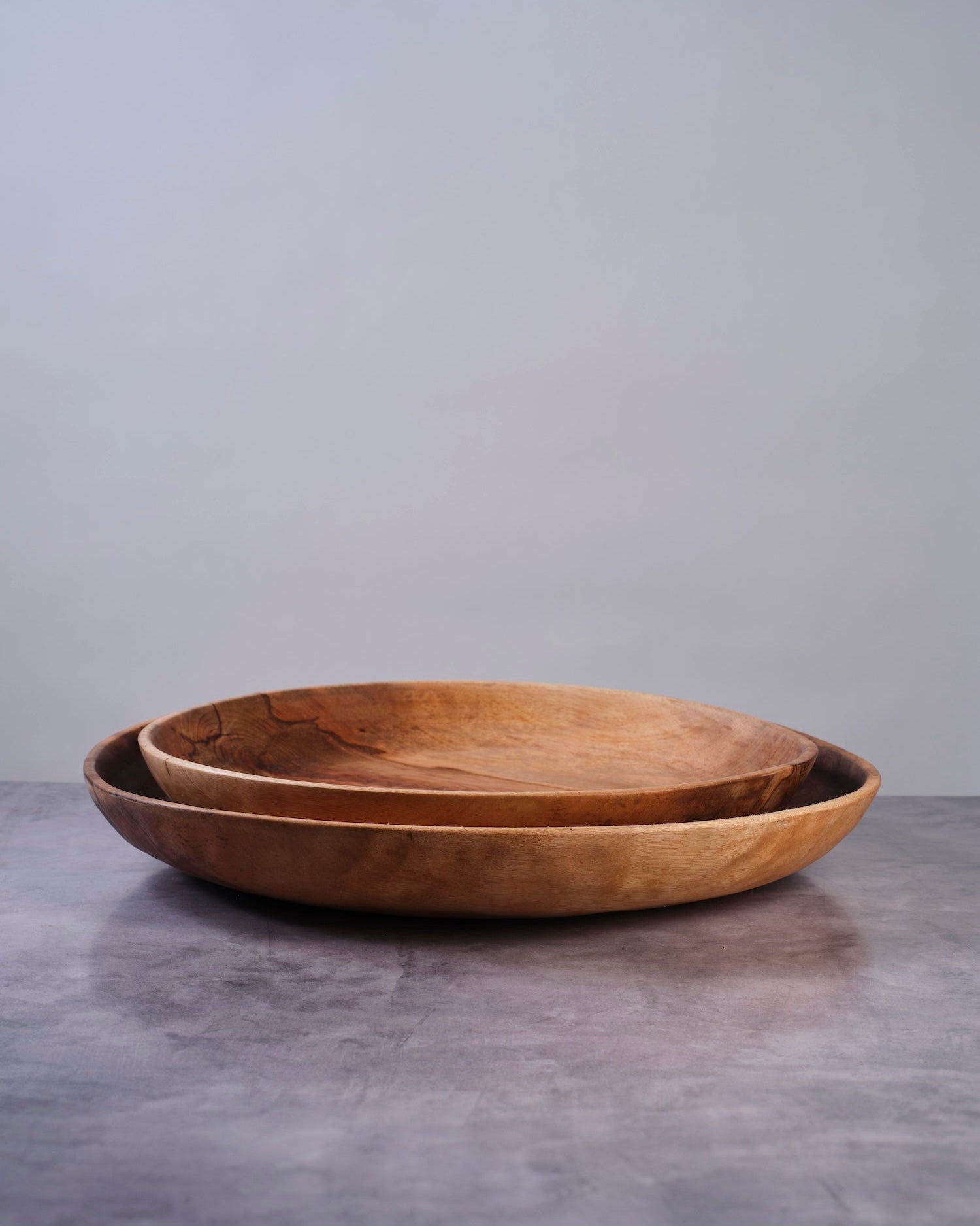 Two wooden bowls on a gray surface with a gray background