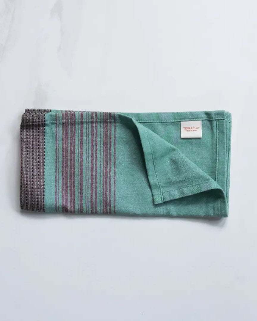 Folded large teal cotton napkins with brown stripes from TerraKlay on a marble surface.