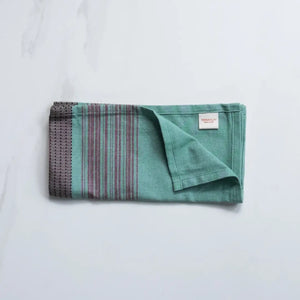 Folded large teal cotton napkins with brown stripes from TerraKlay on a marble surface.