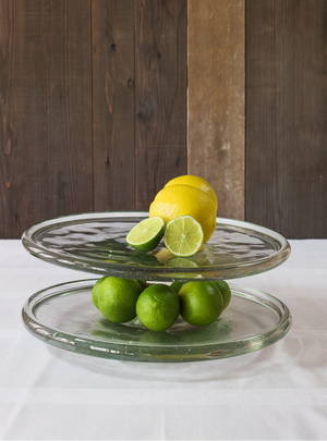 Two-tiered glass plate serving tray with lemons and limes.