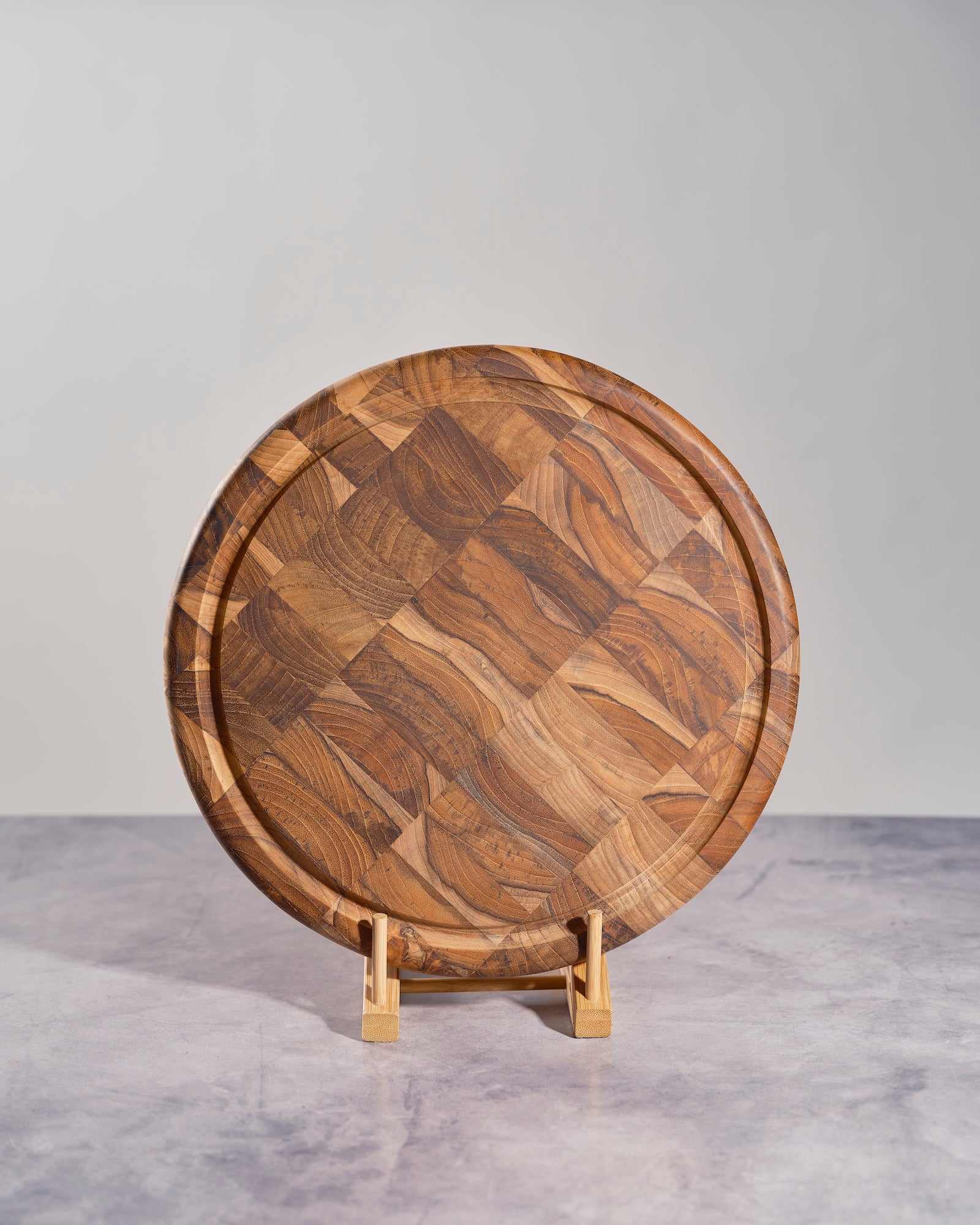 Wooden cutting board with a wavy pattern on a stand against a gray background