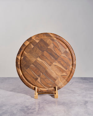 Wooden cutting board with a wavy pattern on a stand against a gray background