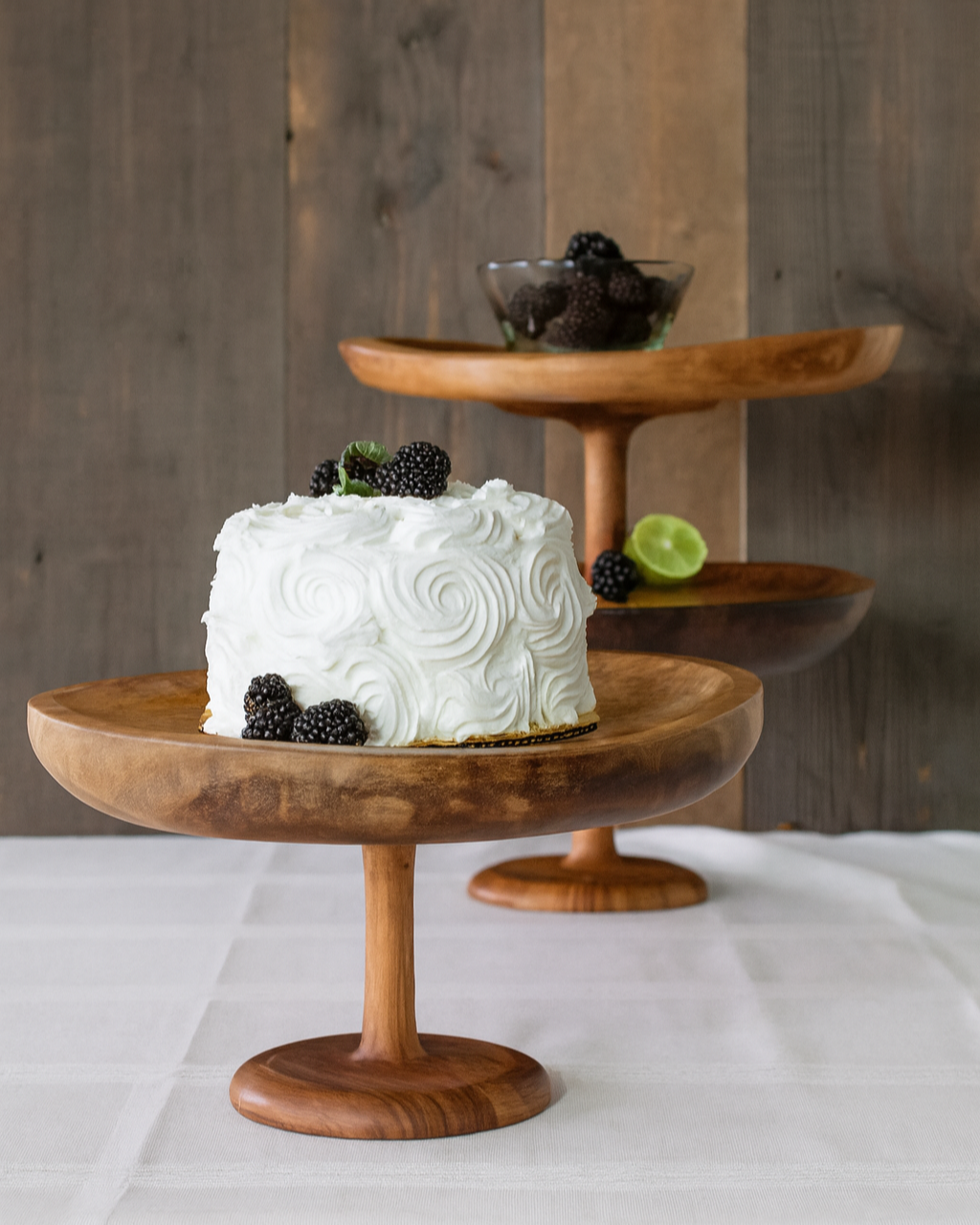 White frosted cake on a Large wooden stand by TerraKlay with blackberries